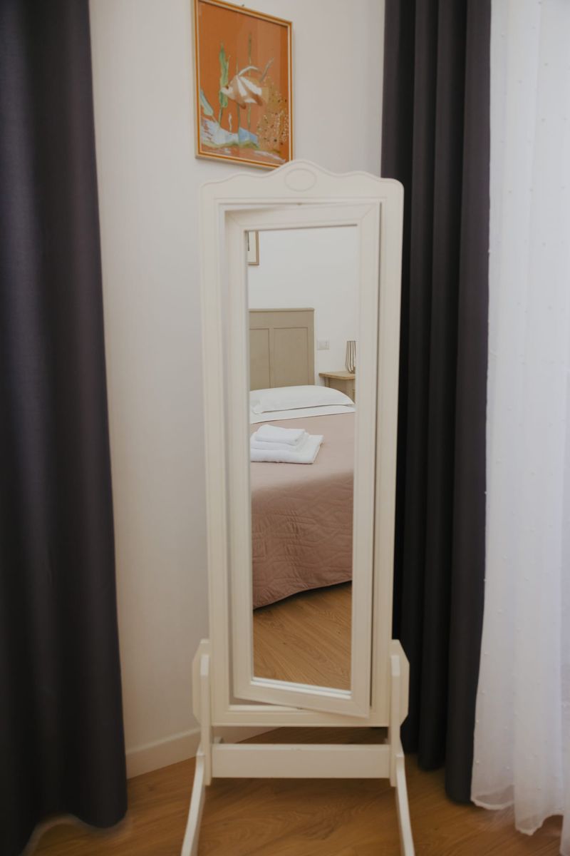 Specchio a bilico bianco che riflette il letto della camera rosa